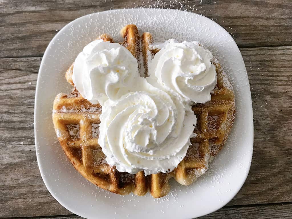 A funnel cake waffle with Mickey Mouse-shaped whipped cream