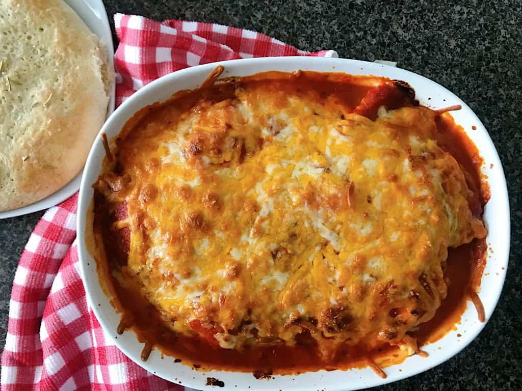 Baked ravioli in a dish with a loaf of rosemary bread