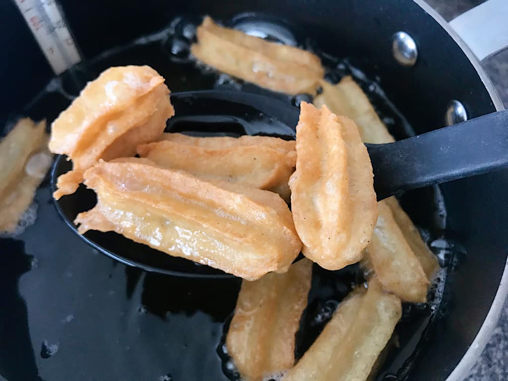 A slotted spoon with mini churros