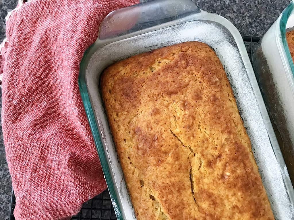 Banana Bread in a loaf pan with a kitchen towel.