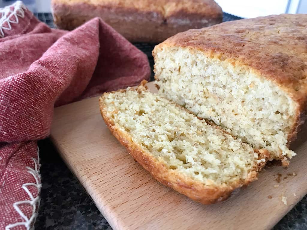 Banana bread with a slice and a red kitchen towel