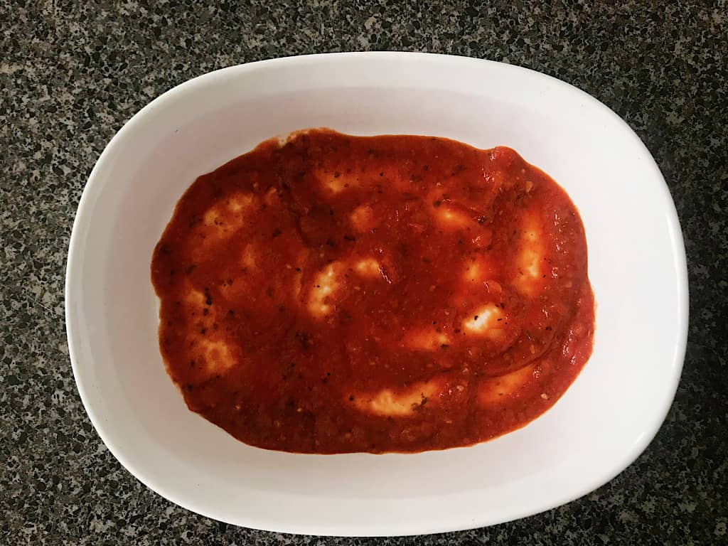 Pasta sauce in the bottom of a baking dish