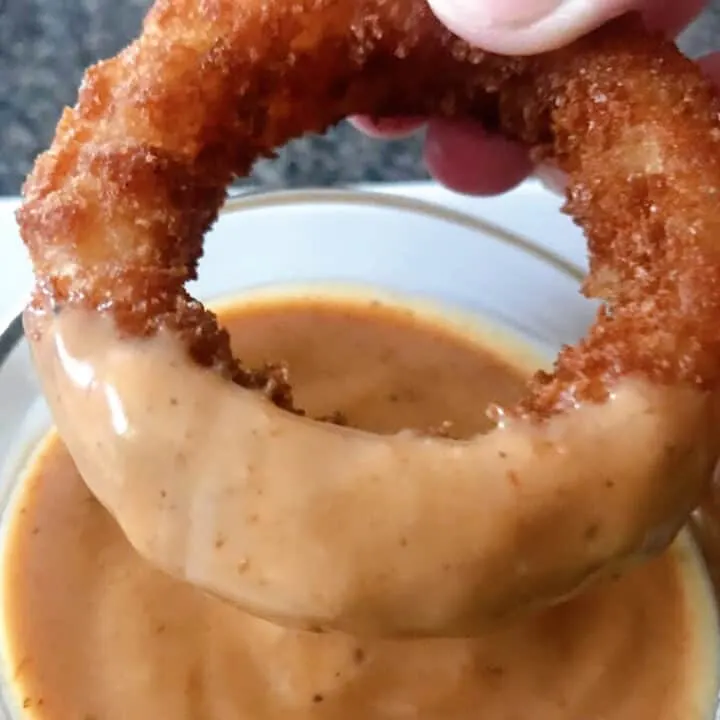 An onion ring dipped in homemade Red Robin Onion Ring Sauce