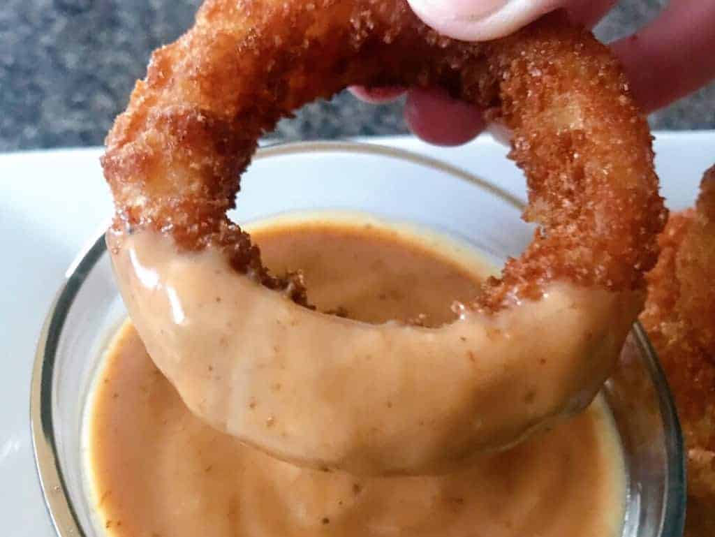 An onion ring dipped in homemade Red Robin Onion Ring Sauce