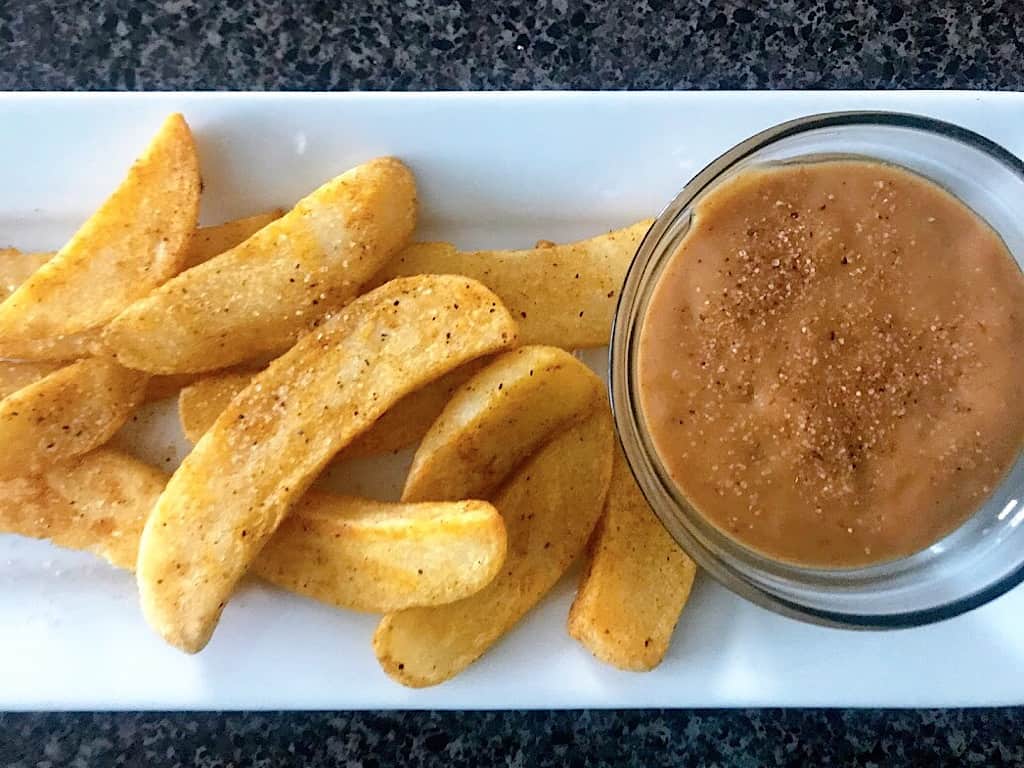 A plate of fries and Red Robin Onion Ring Campfire Sauce