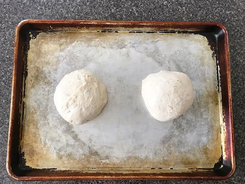 Punch down the dough and divide it in half. Shape the dough into two oval/square loaves and place them on a greased baking sheet.