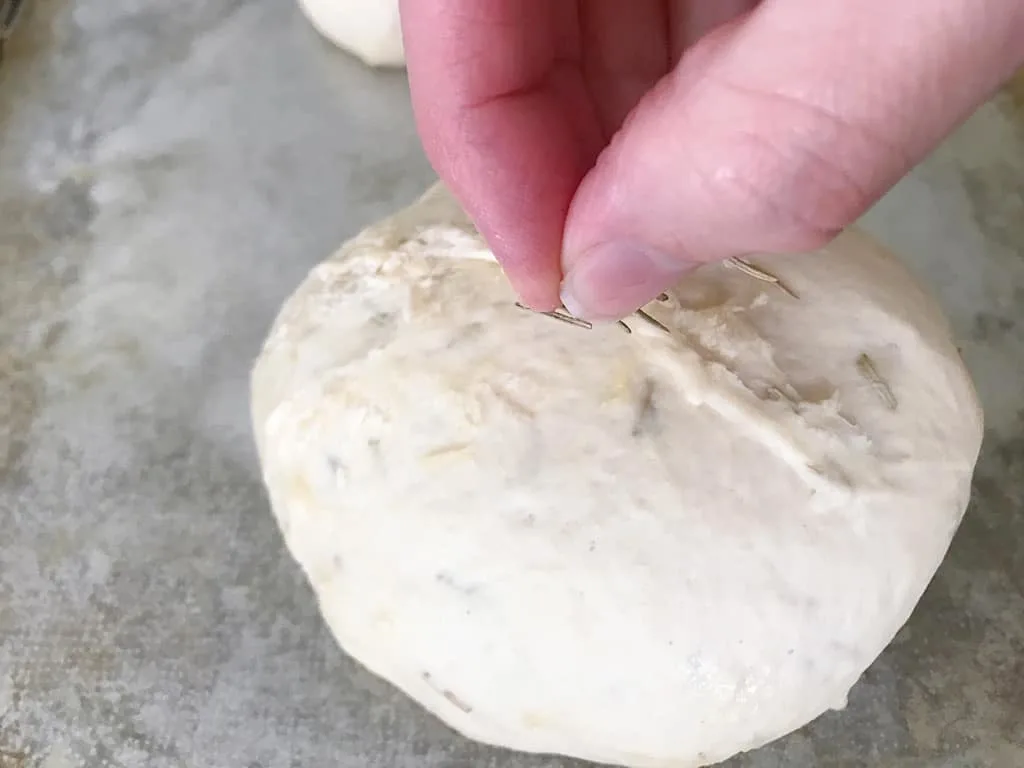 Use a pastry brush to spread the melted butter over the tops of the loaves and sprinkle with the remaining rosemary.