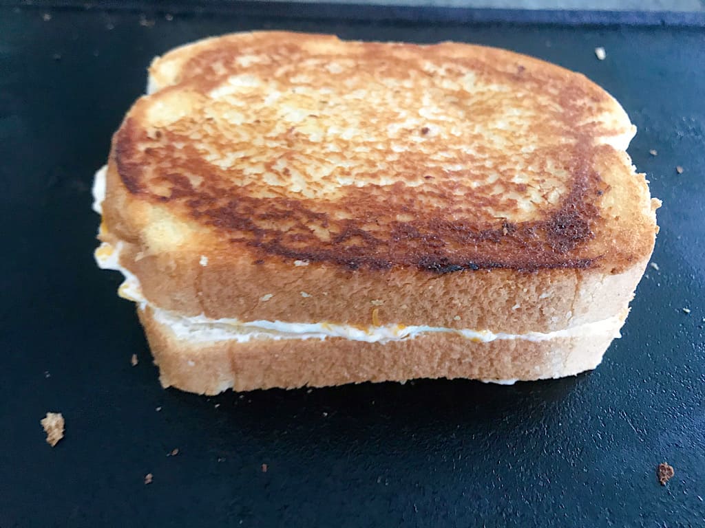 Three cheese grilled cheese on a hot griddle