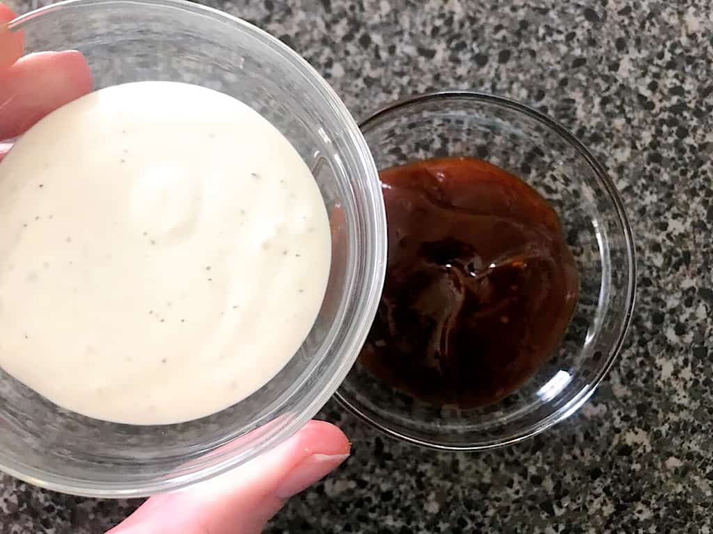 A bowl of ranch dressing and a bowl of barbecue sauce.