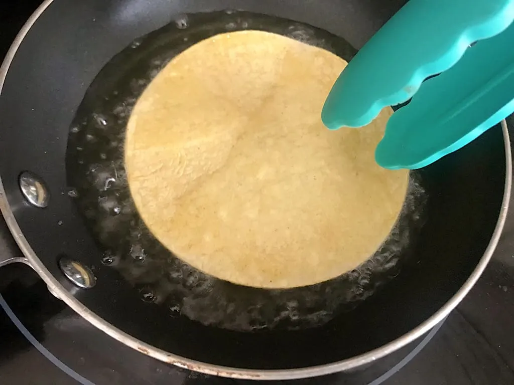 Using tongs, place the tortillas in the hot oil for about 10 seconds on each side until the tortilla begins to bubble.