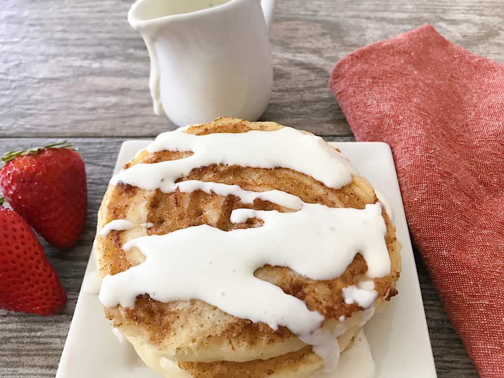 A plate of cinnamon roll pancakes with icing