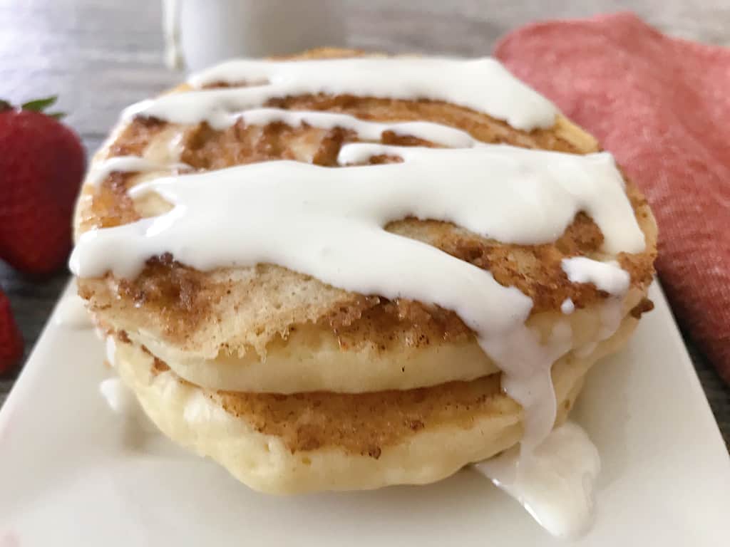 Cinnamon roll pancakes drizzled with cream cheese icing