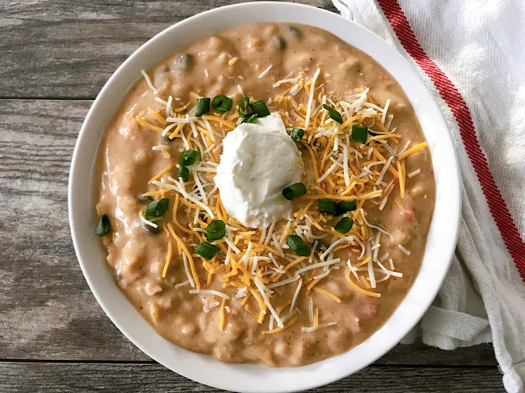 A bowl of Disneyland's Cheesy Enchilada Soup topped with sour cream and green onions