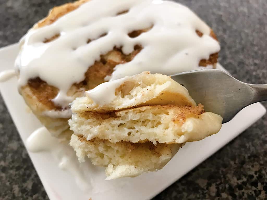 A fork with a bite of cinnamon roll pancakes