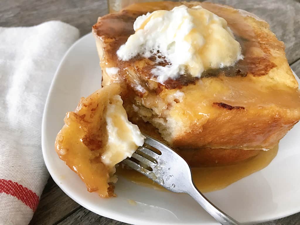 A fork and two slices of homemade Chunky Cinnamon French Toast with caramel syrup