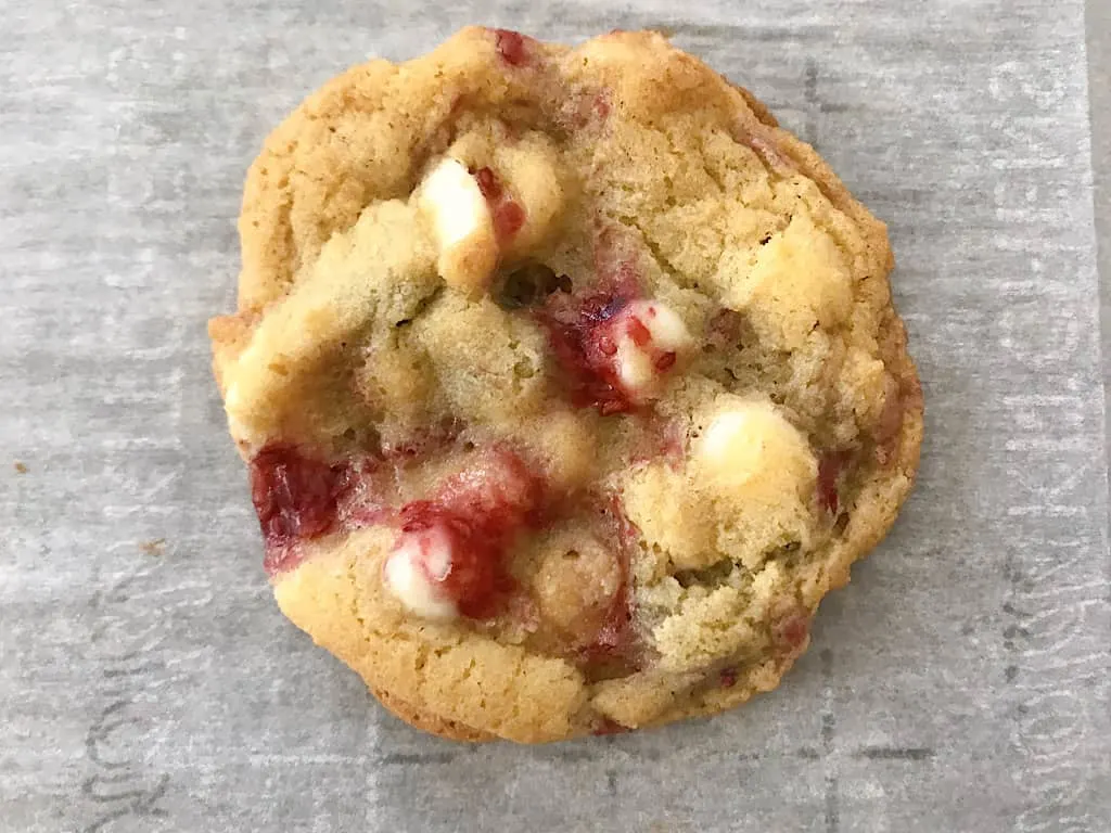 A Raspberry White Chocolate Chip Cookie on parchment paper