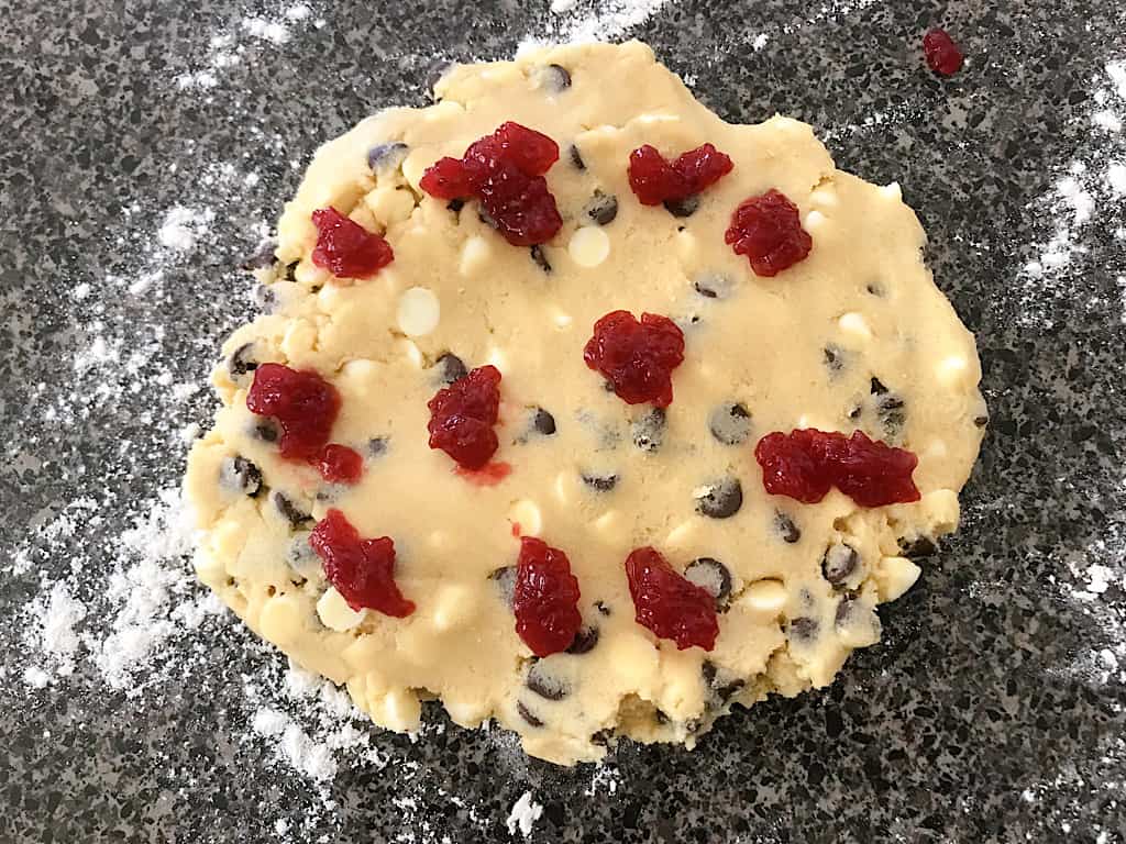 Take half of the cookie dough and press it down flat and place small spoonfuls of raspberry preserves all over the top of the dough.