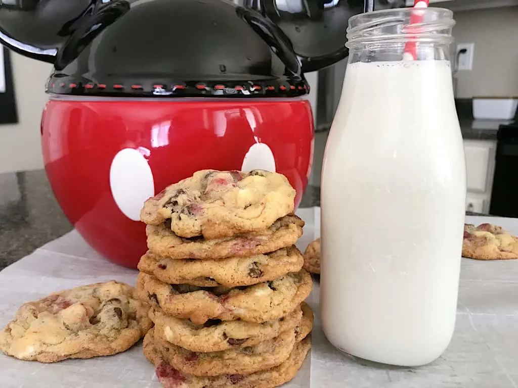 Disneyland Raspberry White Chip Cookies with a glass of milk and a Mickey Mouse Cookie Jar