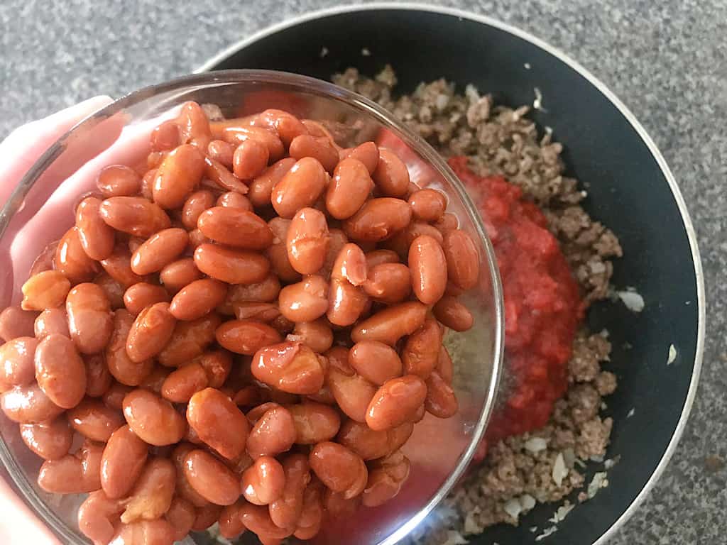 Mix in the crushed tomatoes, tomato sauce, and chili beans.