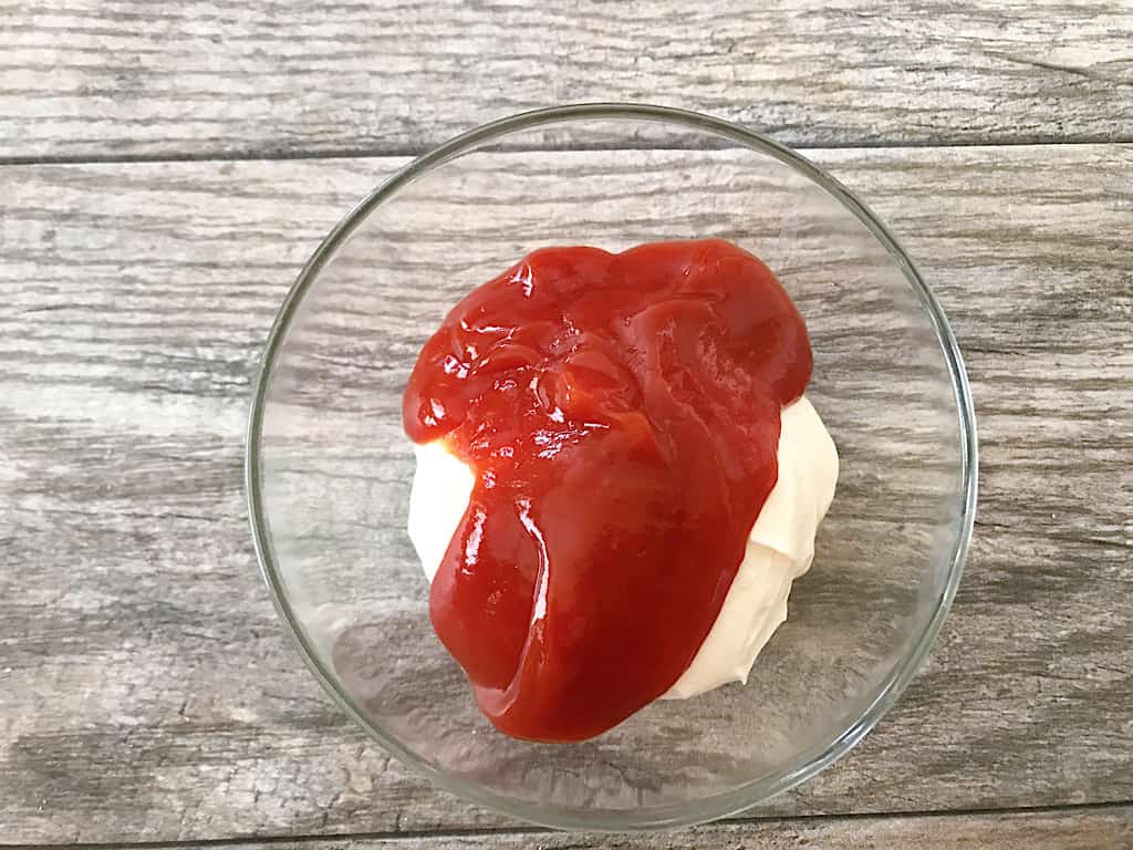 First, measure and add the mayonnaise and ketchup to a mixing bowl.