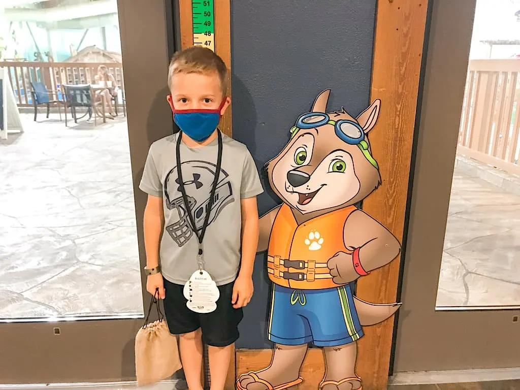 A child next to a cartoon wolf at Great Wolf Lodge water park
