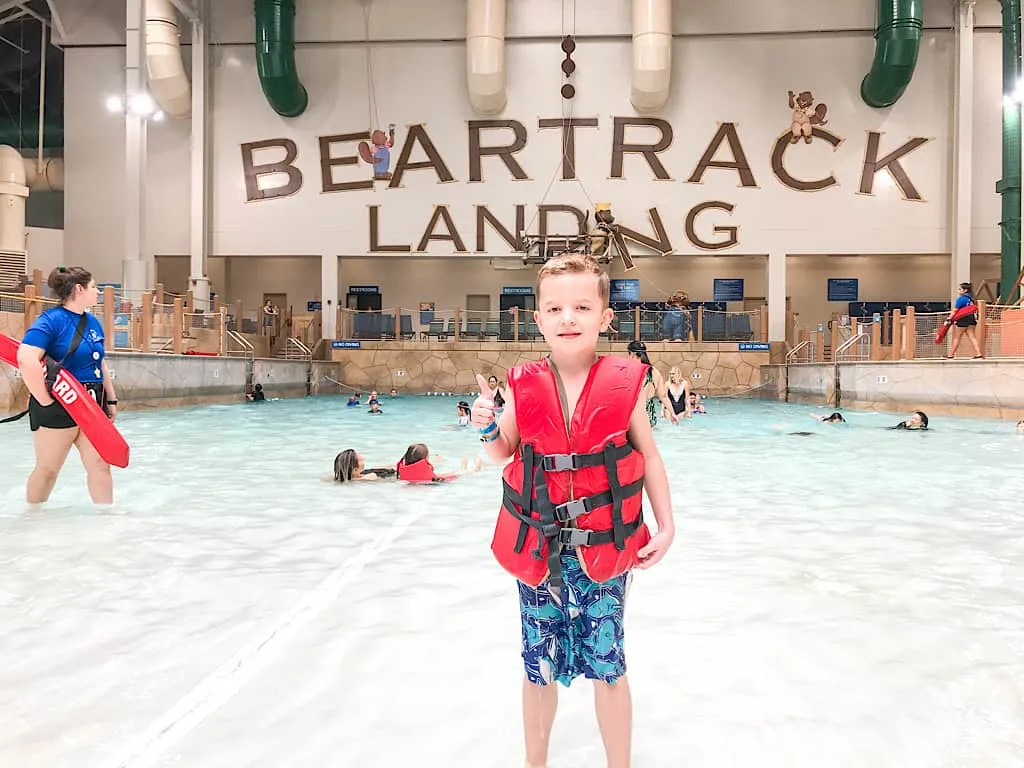 A boy in a life jacket at the wave pool