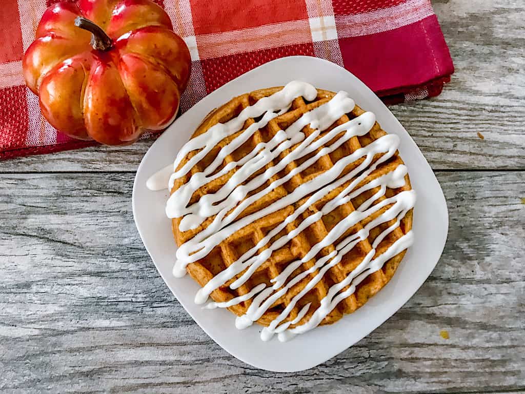 a pumpkin waffle drizzled with cream cheese icing