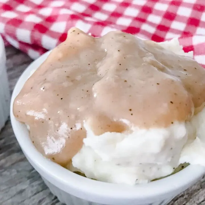 Copycat KFC Mashed Potatoes and Gravy in a white dish and red and white towel.