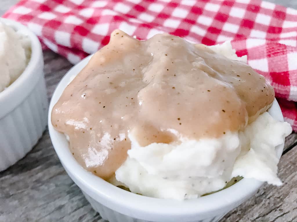 Copycat KFC Mashed Potatoes and Gravy in a white dish and red and white towel.