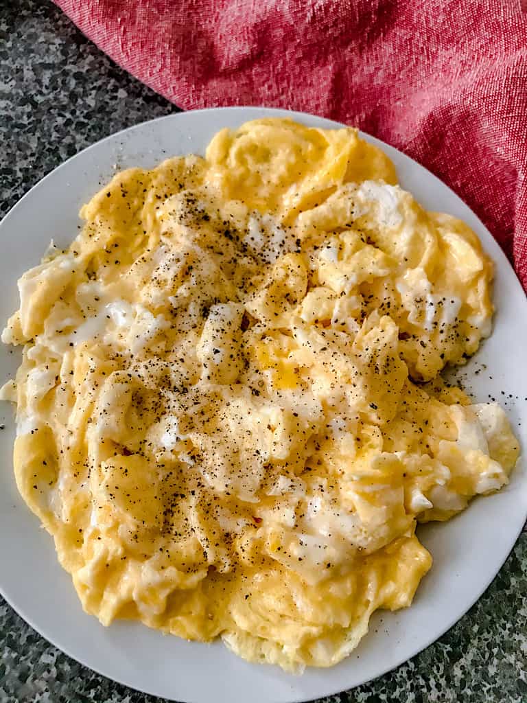 a plate with scrambled eggs and salt and pepper