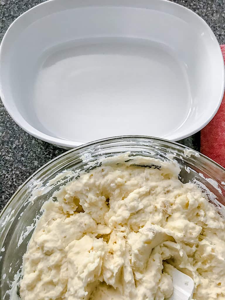 Mashed potatoes in a bowl next to a baking dish.