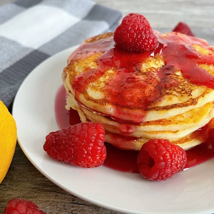 A stack of cheesecake factory copycat lemon ricotta pancakes with raspberry syrup
