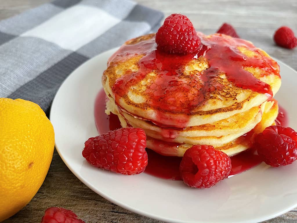 A stack of cheesecake factory copycat lemon ricotta pancakes with raspberry syrup