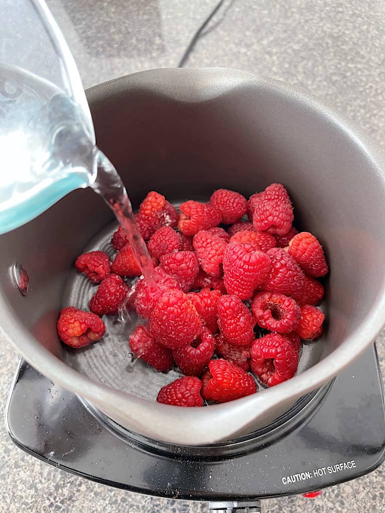 Add the raspberries and 1/2 cup of water to a pan and bring to a boil.