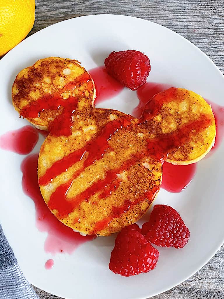 A Mickey-shaped pancake with fresh raspberry syrup