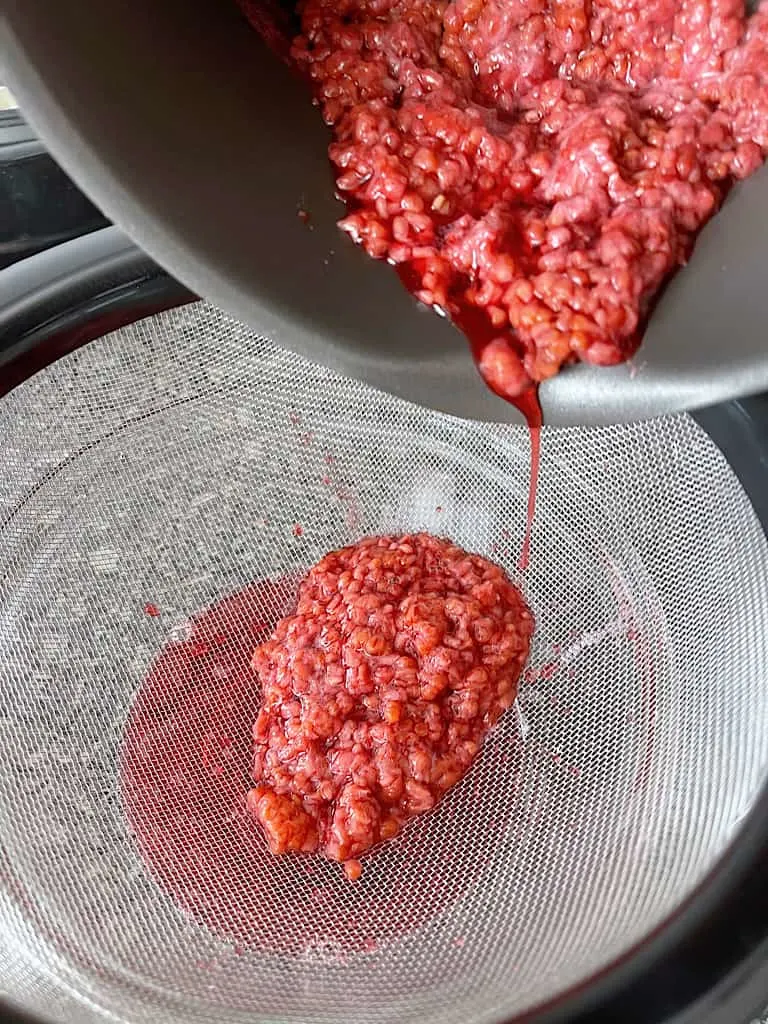 Place a mesh strainer over a bowl and pour in the raspberry mixture.