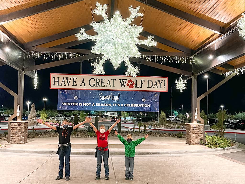 Three kids in face masks at the entrance of Great Wolf Lodge