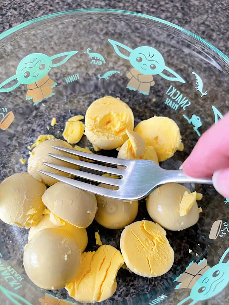 A fork smashing hard boiled egg yolks.