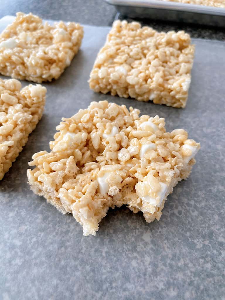 Four Rice Krispie Treats with one having a bite removed.