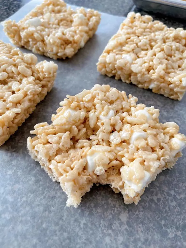 Four Rice Krispie Treats with one having a bite removed