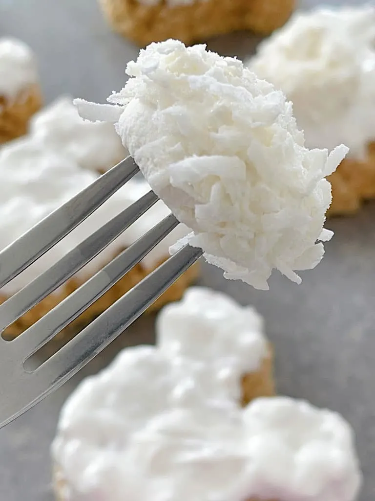 A fork holding a marshmallow covered in coconut flakes.