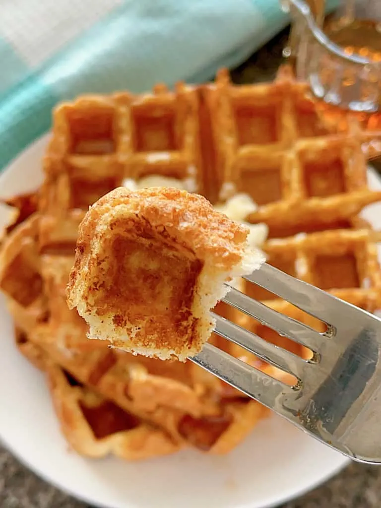 A fork holding a piece of French Toast Waffles.
