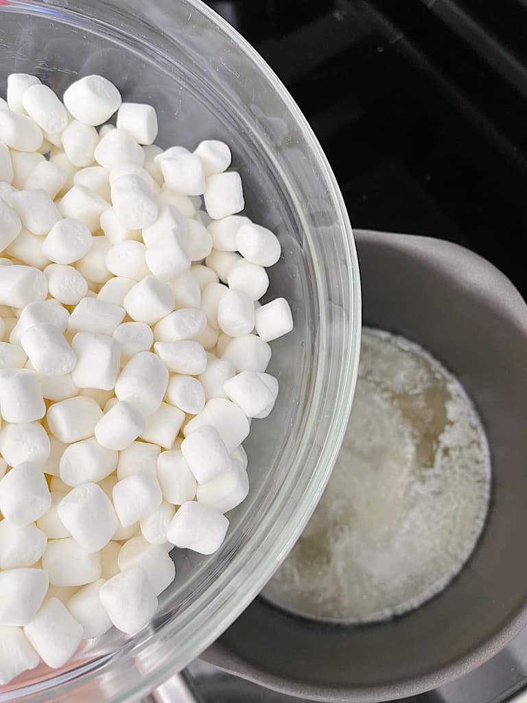 Mini marshmallows in a bowl over a pan of melted butter.