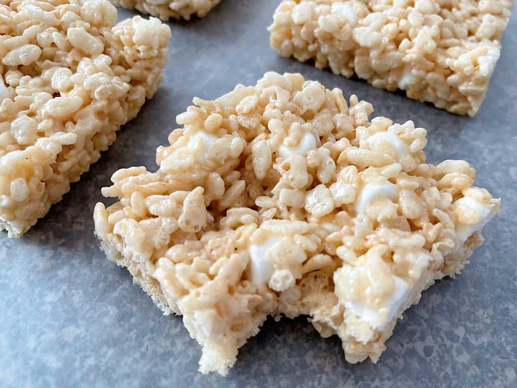 Four Rice Krispie Treats with one having a bite removed