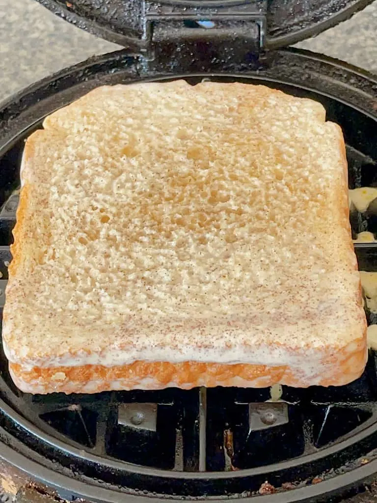 A slice of bread on a waffle iron.