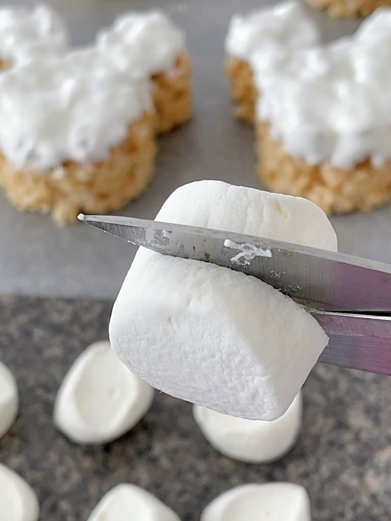 Scissors cutting a jumbo marshmallow in half.