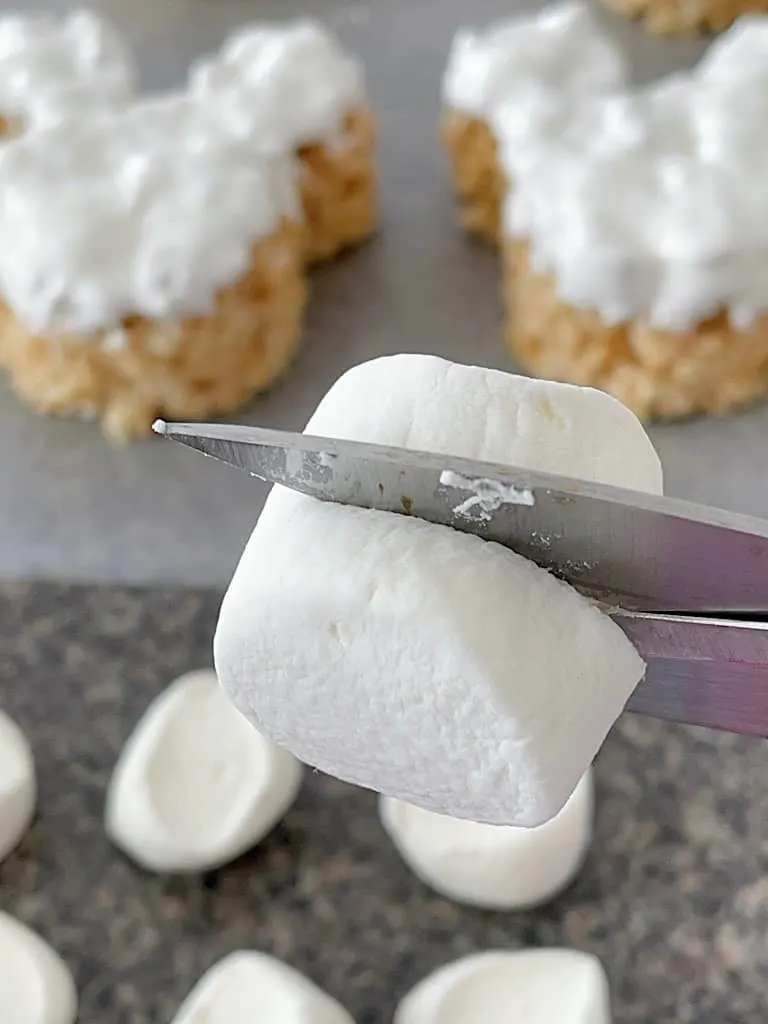 Scissors cutting a jumbo marshmallow in half.