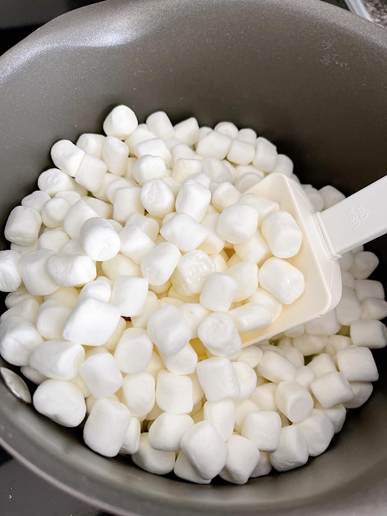 A spatula stirring marshmallows in a pan.