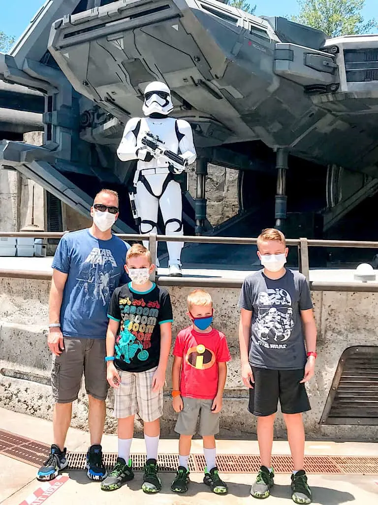 A dad and three boys wearing face masks at Disney World in front of a Storm Trooper.