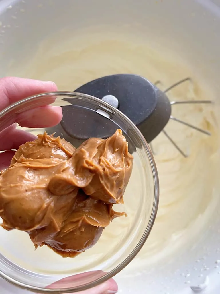 A bowl of peanut butter over a bowl of whipped cream.